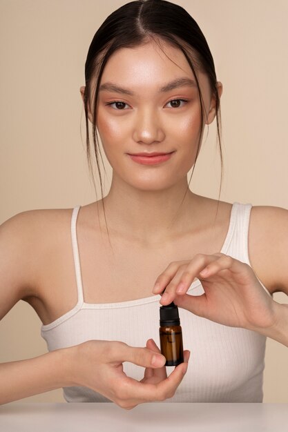 Front view korean woman posing with serum bottle