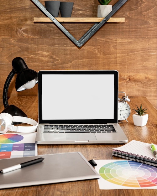 Front view of laptop on office workspace with lamp and notebook