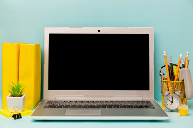 Front view laptop with office supplies on the table