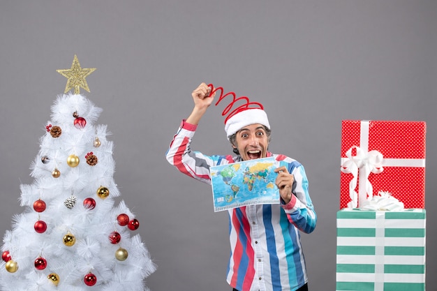 Front view laughing man with spiral spring santa hat holding world map