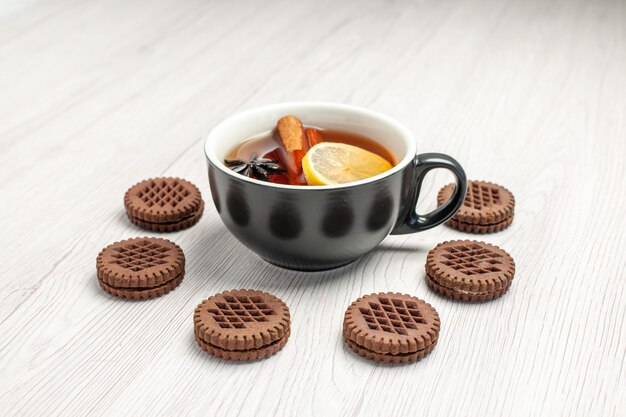 Free photo front view lemon cinnamon tea rounded with cookies on the white wooden background