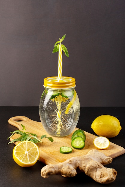어두운 배경 칵테일 음료 과일에 꽃 짚과 유리 컵 슬라이스 및 전체 레몬 오이 안에 전면보기 레몬 칵테일 신선한 시원한 음료