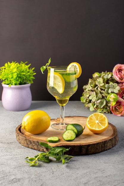 나무 책상과 회색 배경 칵테일 음료 과일에 유리 슬라이스 레몬 빨대 안에 전면보기 레몬 칵테일 신선한 시원한 음료