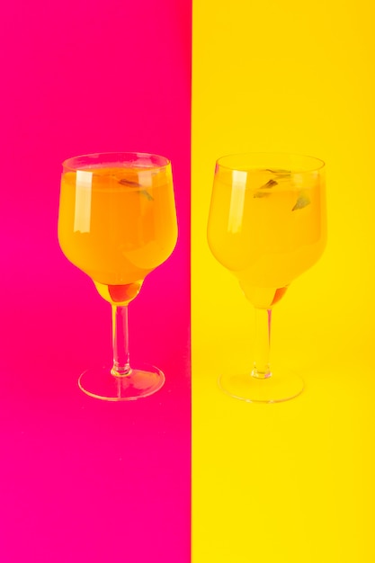 A front view lemon drink fresh cool icing inside glasses isolated on the yellow-pink background cocktail drink summer