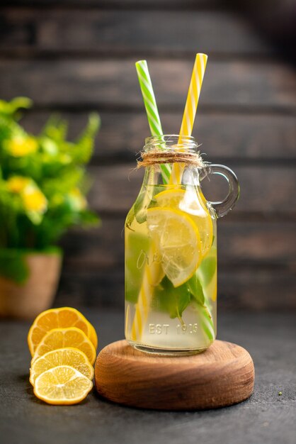 Front view lemonade on wooden serving board lemon slices potted plant on brown surface