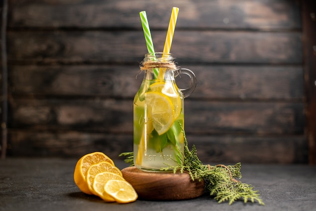 Front view lemonade yellow and green pipettes on wood board cut lemons on wooden surface