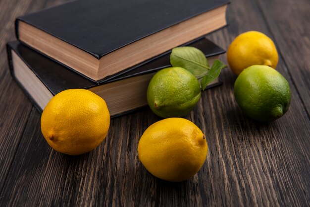 Лимоны с лаймом и книги на деревянном фоне вид спереди