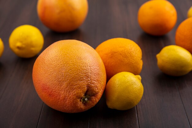 Front view lemons with oranges and grapefruits on wood background