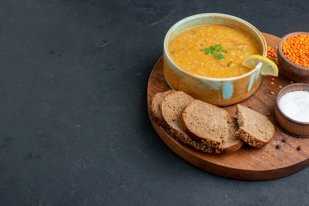 Free photo front view lentil soup with salt raw lentils and dark bread loafs on dark surface