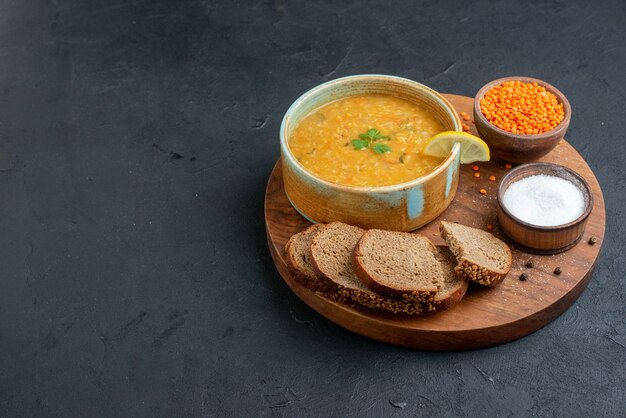 Front view lentil soup with salt raw lentils and dark bread loafs on dark surface