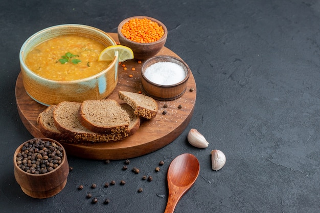 Front view lentil soup with salt raw lentils and dark bread loafs on dark surface