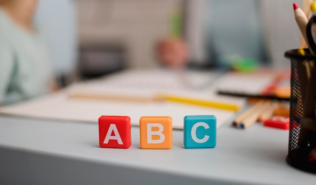 Front view of letters on cubes with defocused tutoring session in the back