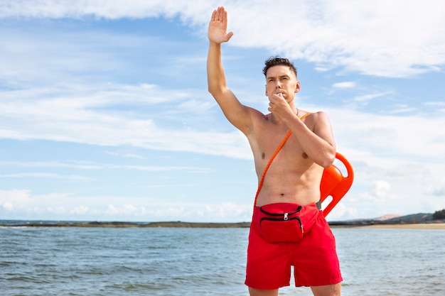 Free photo front view lifeguard blowing whistle