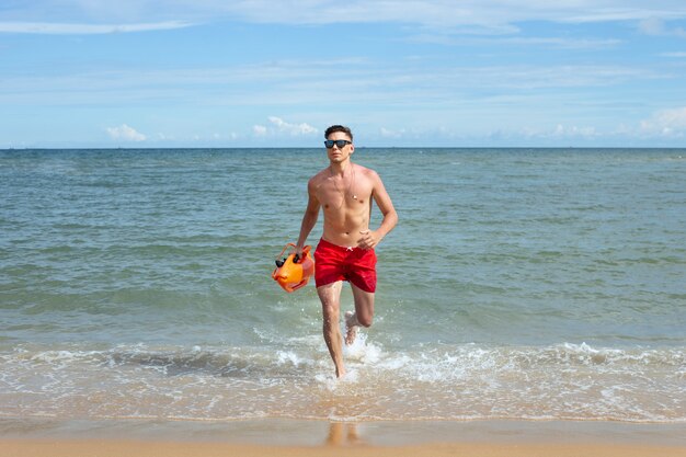 Front view lifeguard running on the beach