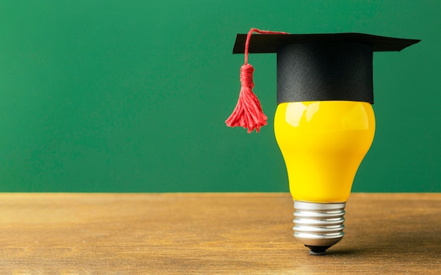 Front view of lightbulb with academic cap and copy space