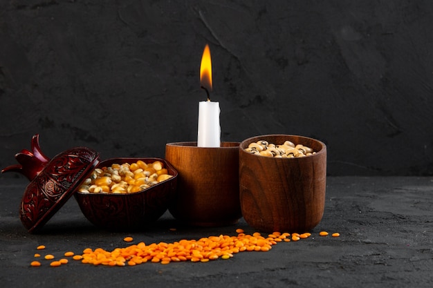 Вид спереди зажженная свеча с бобами кукурузы и чечевицы