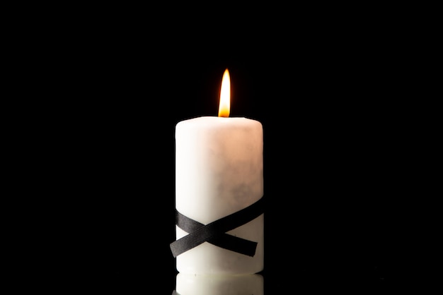 Front view of lighting candle on black