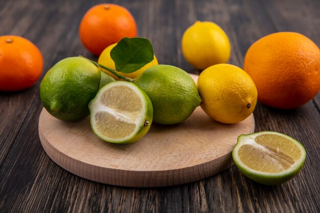 Front view limes with lemons on a stand with oranges on a wooden background