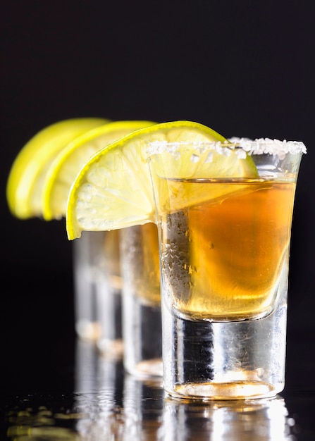 Front view line of gold tequila shots  with lime slices