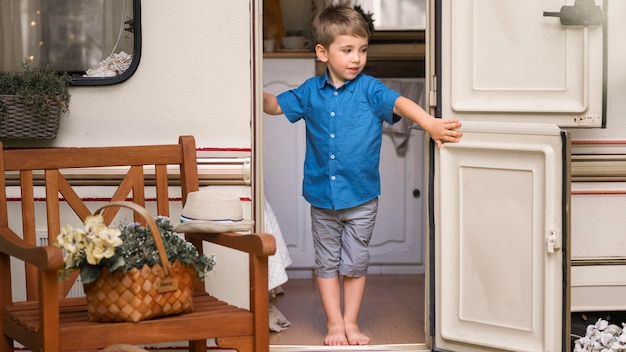 Free photo front view little boy opening a caravan's door