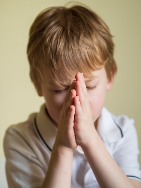 Вид спереди маленького мальчика молиться