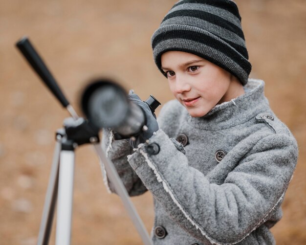 Front view little boy using a telescope