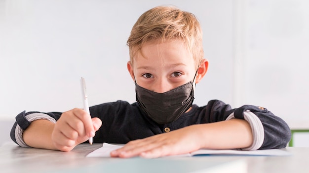 Free photo front view little boy wearing a black medical mask