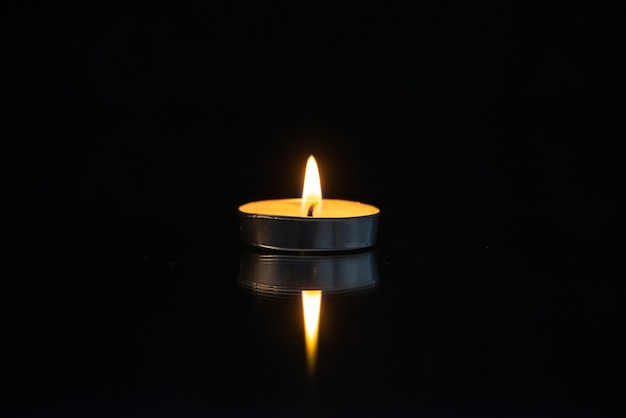 Вид спереди маленькой горящей свечи на черном