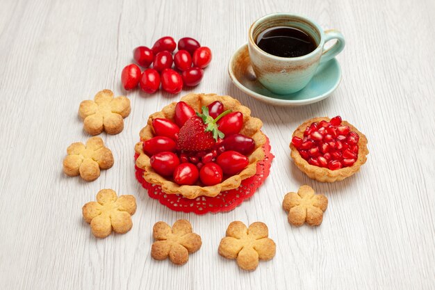 Front view little cake with fruits and cup of tea on white desk fruit dessert cake