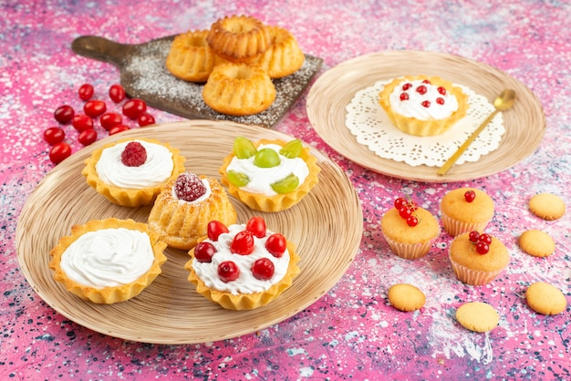 Front view little cakes with fresh cream and fruits on the bright surface cookie