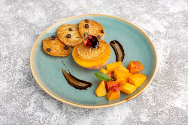 Front view little cookie pastries inside plate with fresh sliced peaches on light table, cake biscuit sugar sweet pastry fruit