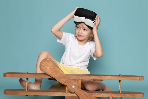 front view little cute boy playing vr goggles in white t-shirt on the blue floor