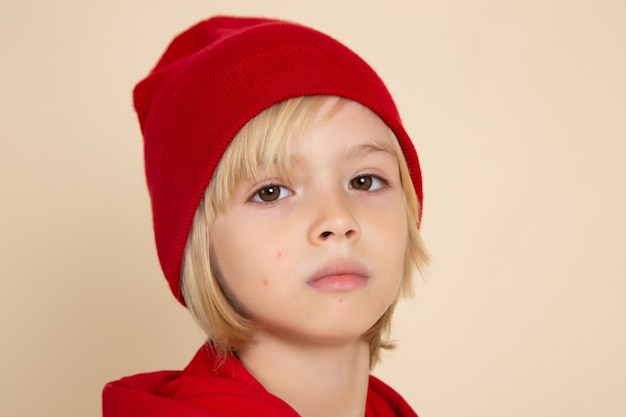 빨간 셔츠와 흰색 벽에 모자에 전면 보기 작은 귀여운 소년