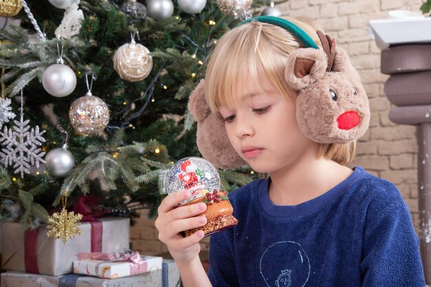 Вид спереди маленький милый мальчик, сидящий вокруг рождественской елки и подарков