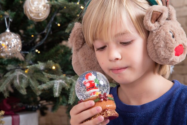 Front view little cute boy sitting around xmas tree