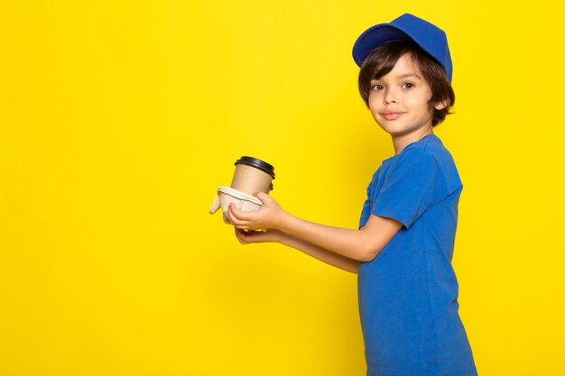 A front view little cute courier in blue t-shirt blue cap holding coffee cups