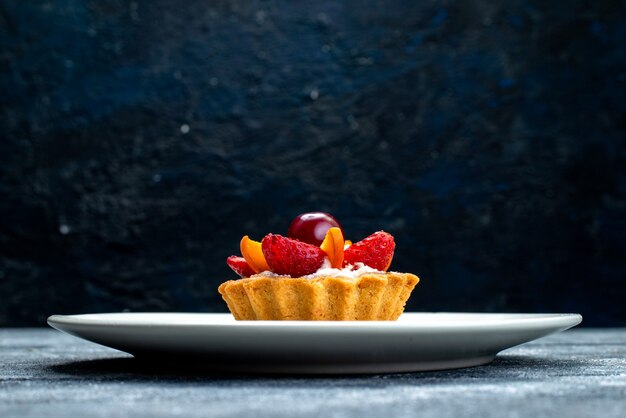 Вид спереди маленький вкусный торт со сливками и фруктами внутри белой тарелки на серо-синем столе фруктовый торт бисквит