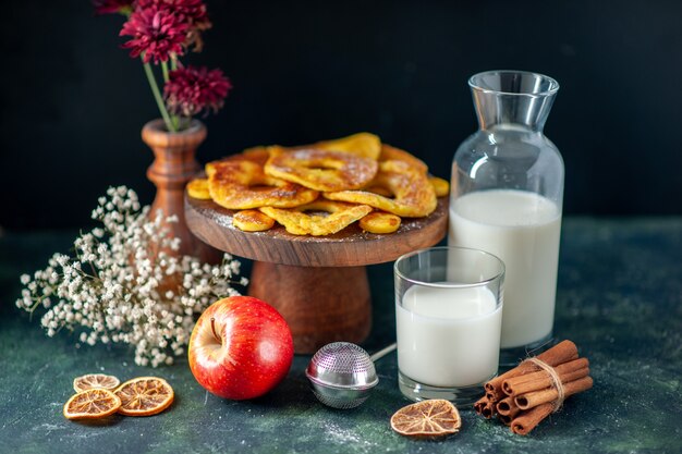 Вид спереди маленькие вкусные пирожные в форме кольца ананаса с молоком на темном горячем пироге выпечка пирога цветное печенье торт фруктовое бисквитное тесто