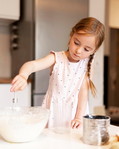 Vista frontale della bambina che cucina a casa