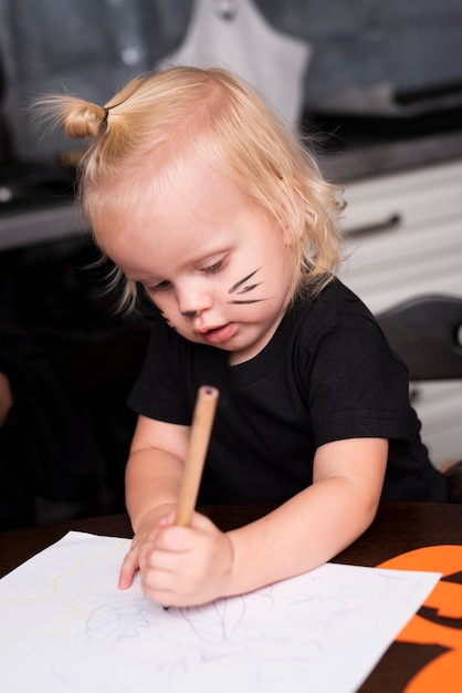 Free photo front view of little girl drawing in the kitchen