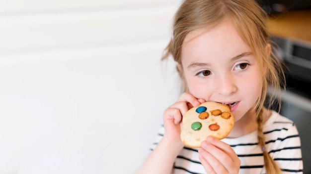 Foto gratuita vista frontale della bambina che mangia un biscotto