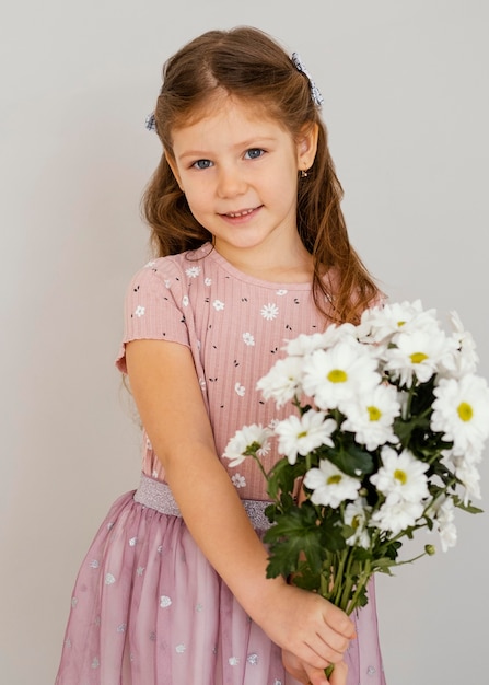 Front view of little girl holding bouquet of spring flowers