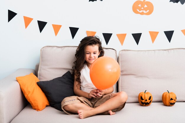 Front view little girl holding a halloween balloon