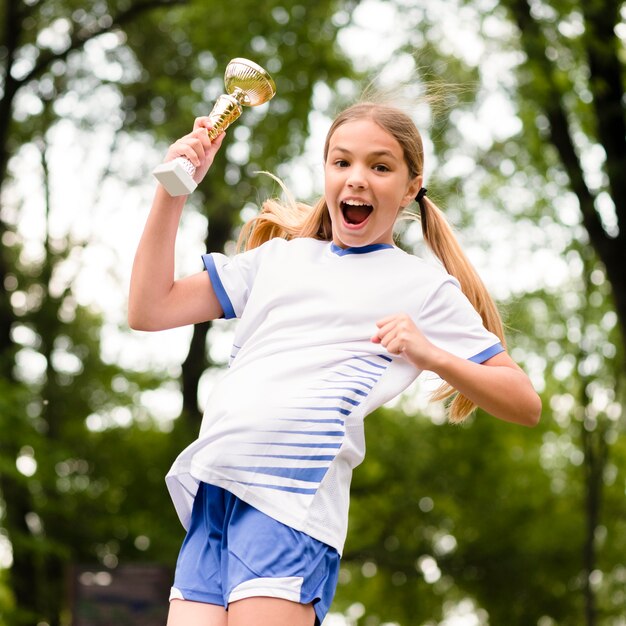 Вид спереди маленькая девочка прыгает после победы в футбольном матче