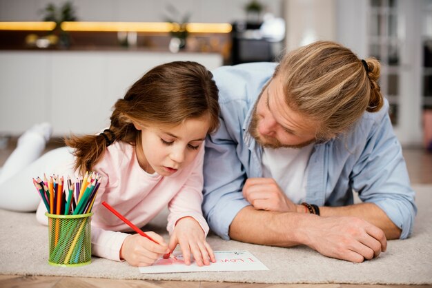 Front view of little girl spending time with father drawing