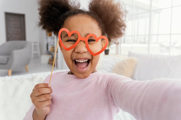 Front view of little girl taking selfie at home