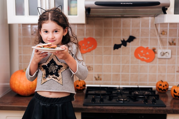 Foto gratuita vista frontale di una bambina con un piatto di biscotti