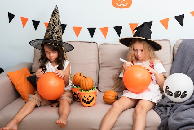 Вид спереди маленьких девочек, сидя на диване на Хэллоуин