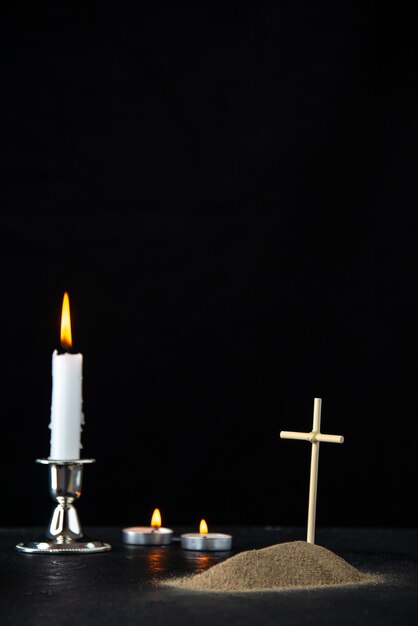 Front view of little grave with candle on black
