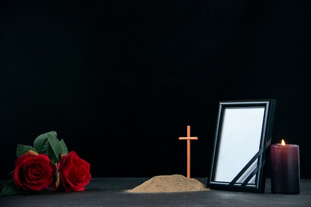 Front view of little grave with candle and picture frame on black